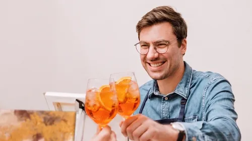 Mann stößt mit Gläsern mit Orangendrinks an.