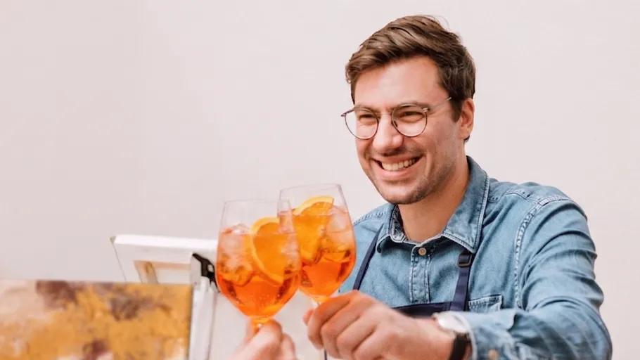 Man clinking glasses with orange drinks.