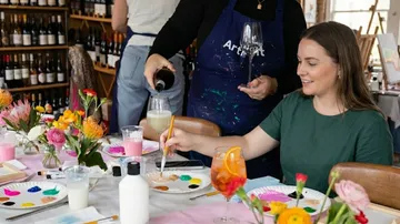 Woman painting during a wine-painting event.