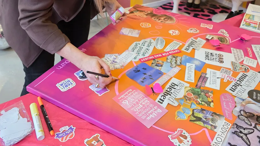 Person bastelt an farbigem Vision Board Tisch.