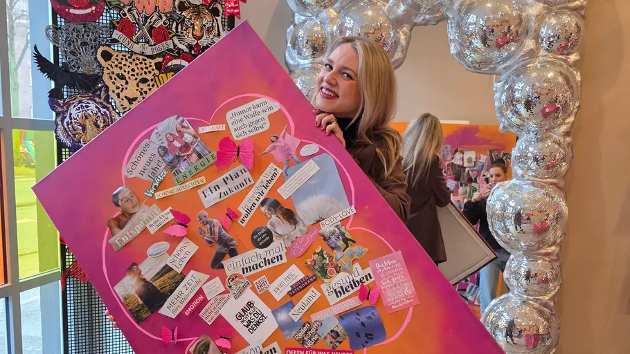 Woman holding colorful collage in exhibition space.