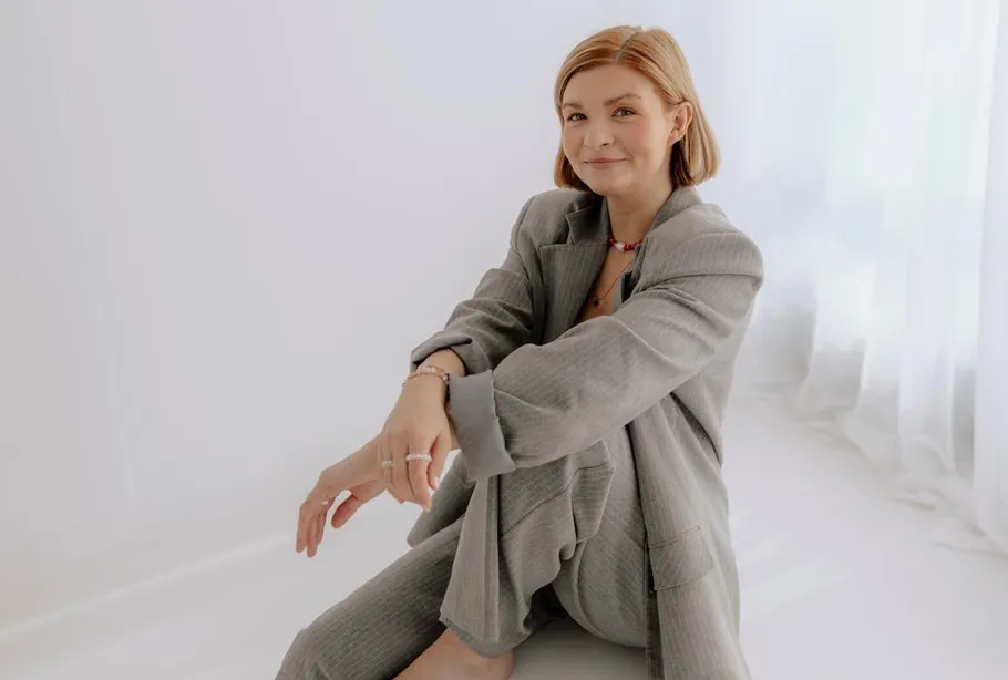 Woman in gray suit sitting on floor.