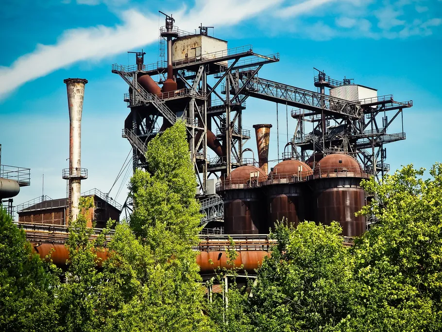 Industrieanlage im Freien, umgeben von Bäumen, bei sonnigem Wetter.