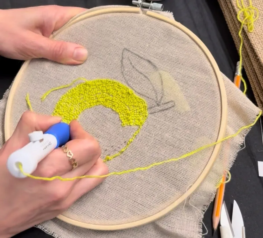 Person using punch needle on canvas hoop.
