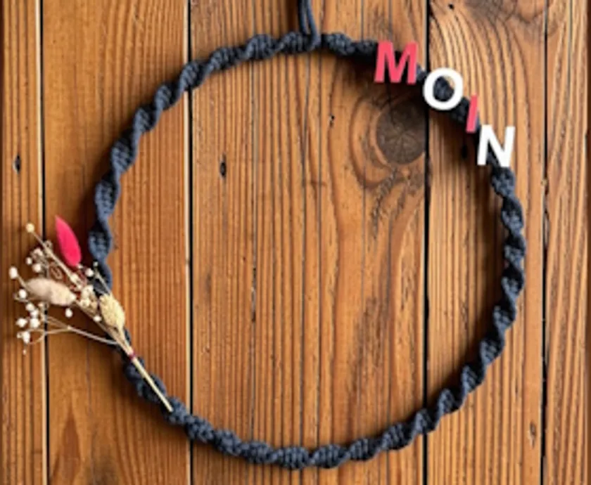 Wreath with "MOIN" and dried flowers on wood.