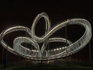 Floating metal spiral, illuminated, people walking.