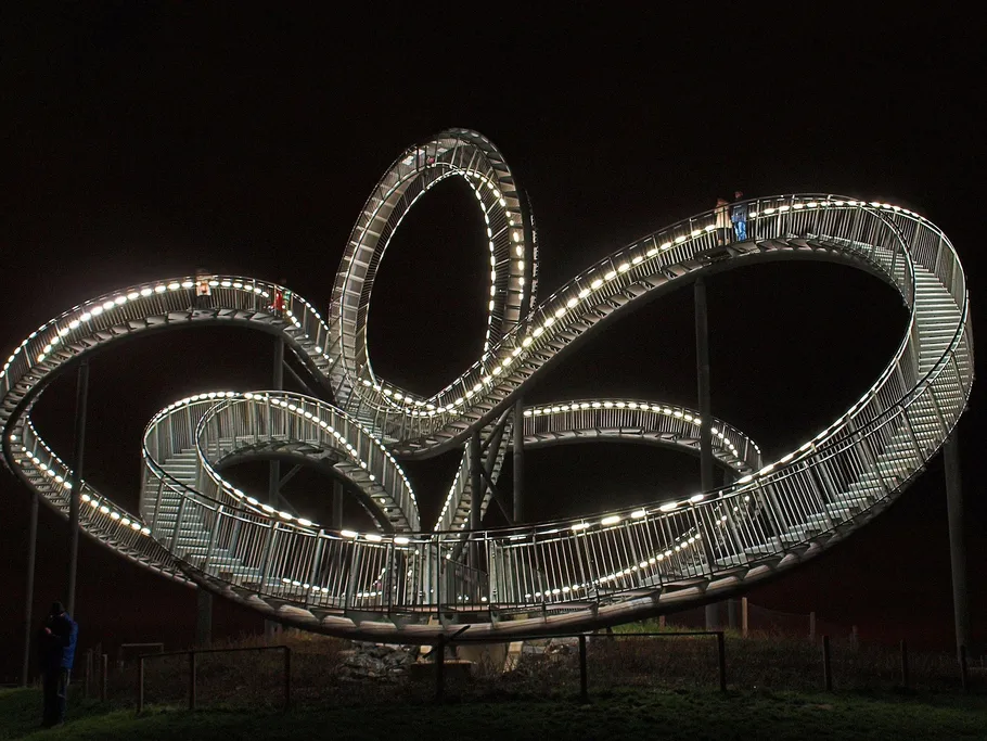 Schwebende Spirale aus Metall, beleuchtet, Menschen gehen.