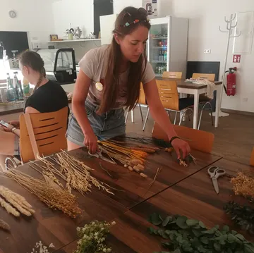 Woman arranging dried flowers on a table.