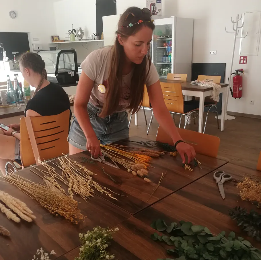 Woman arranging dried flowers on a table.