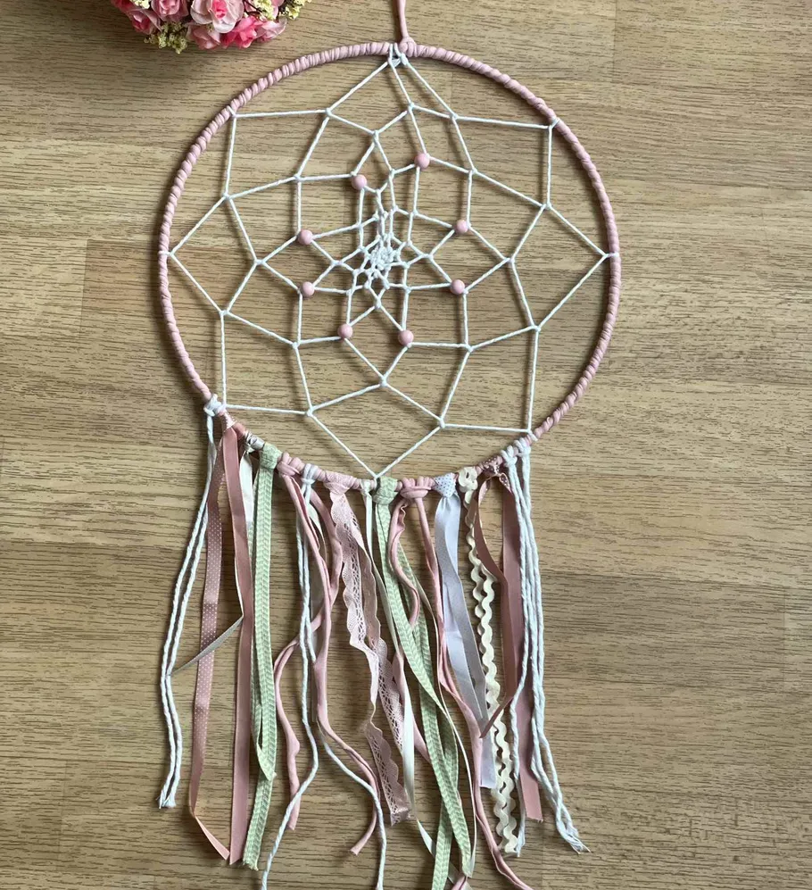 Traumfänger mit rosa Bändern auf Holztisch.