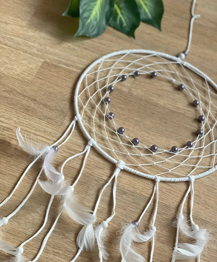 Dreamcatcher with beads and feathers on table.