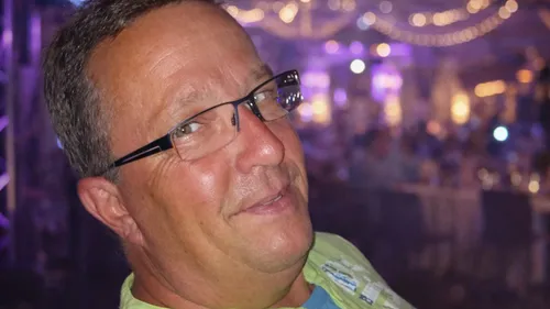Man smiling at indoor event with lights.