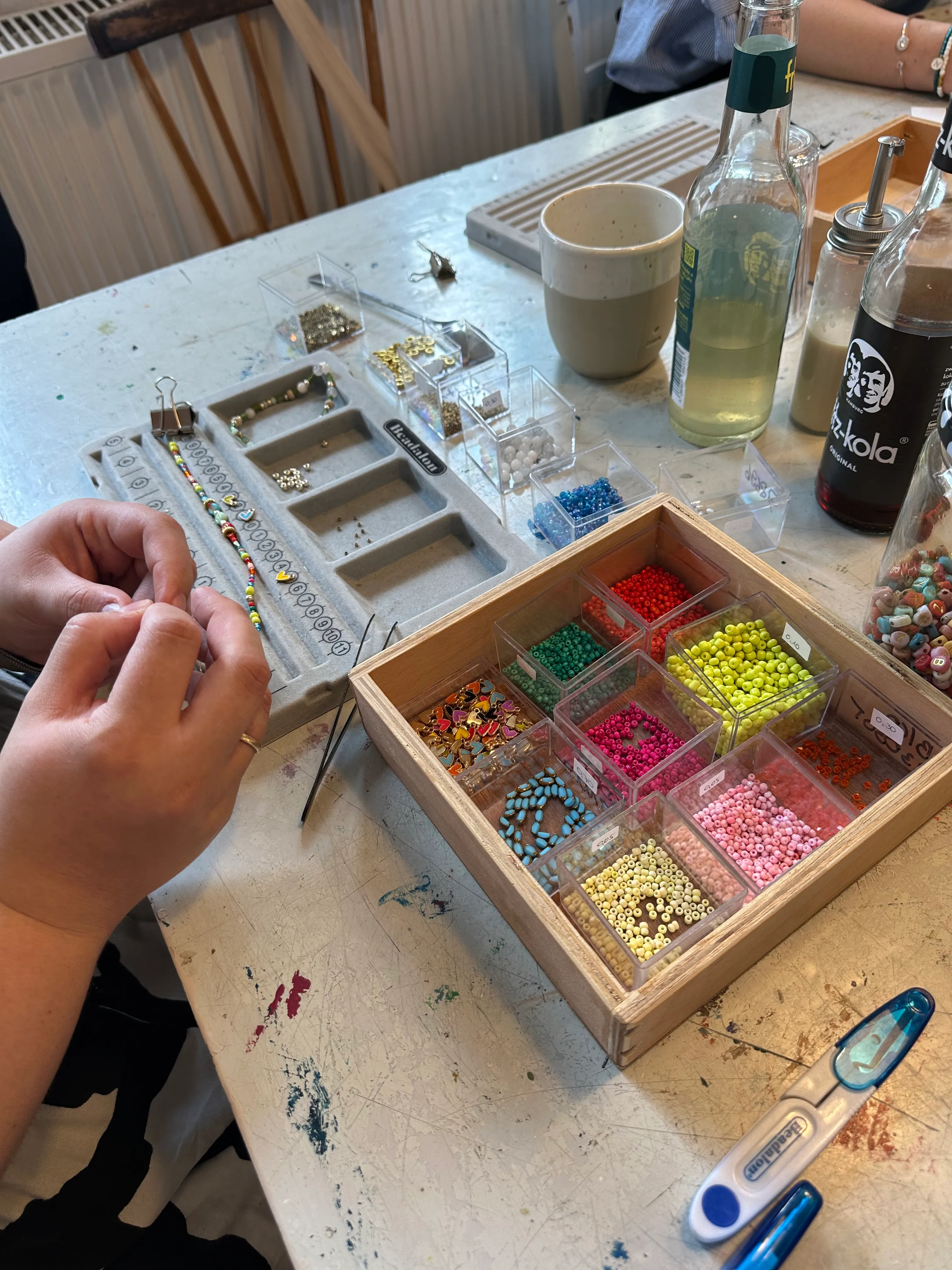 Person macht Schmuck mit bunten Perlen.