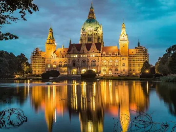 Historic building reflected in water during twilight.