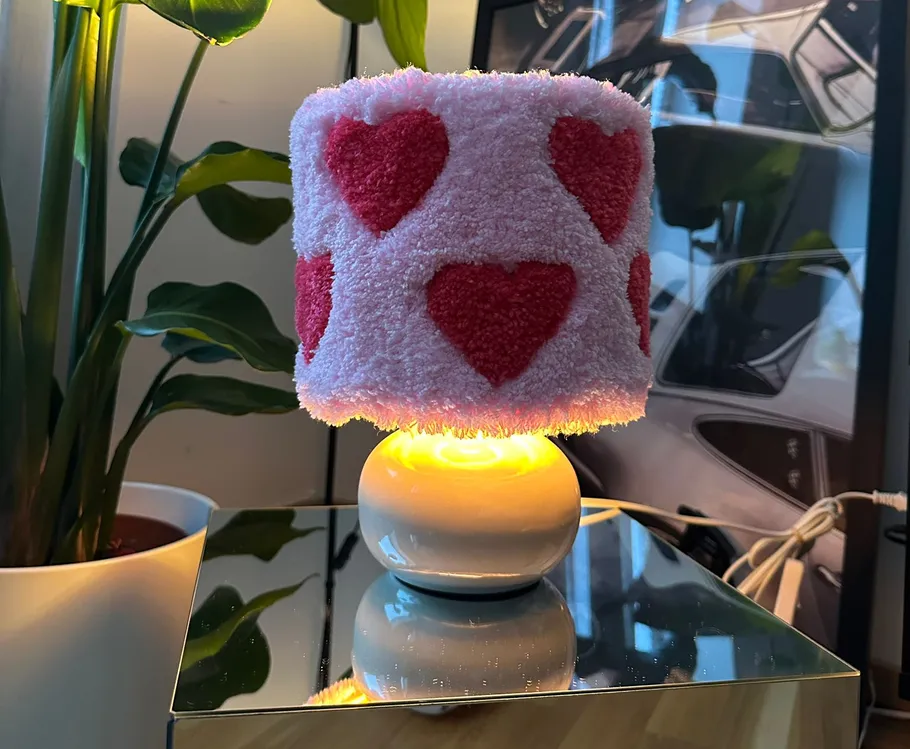 Heart-patterned lamp glowing on mirrored surface.
