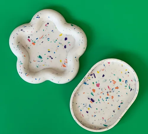 Zwei Terrazzo-Tabletts auf grünem Hintergrund.