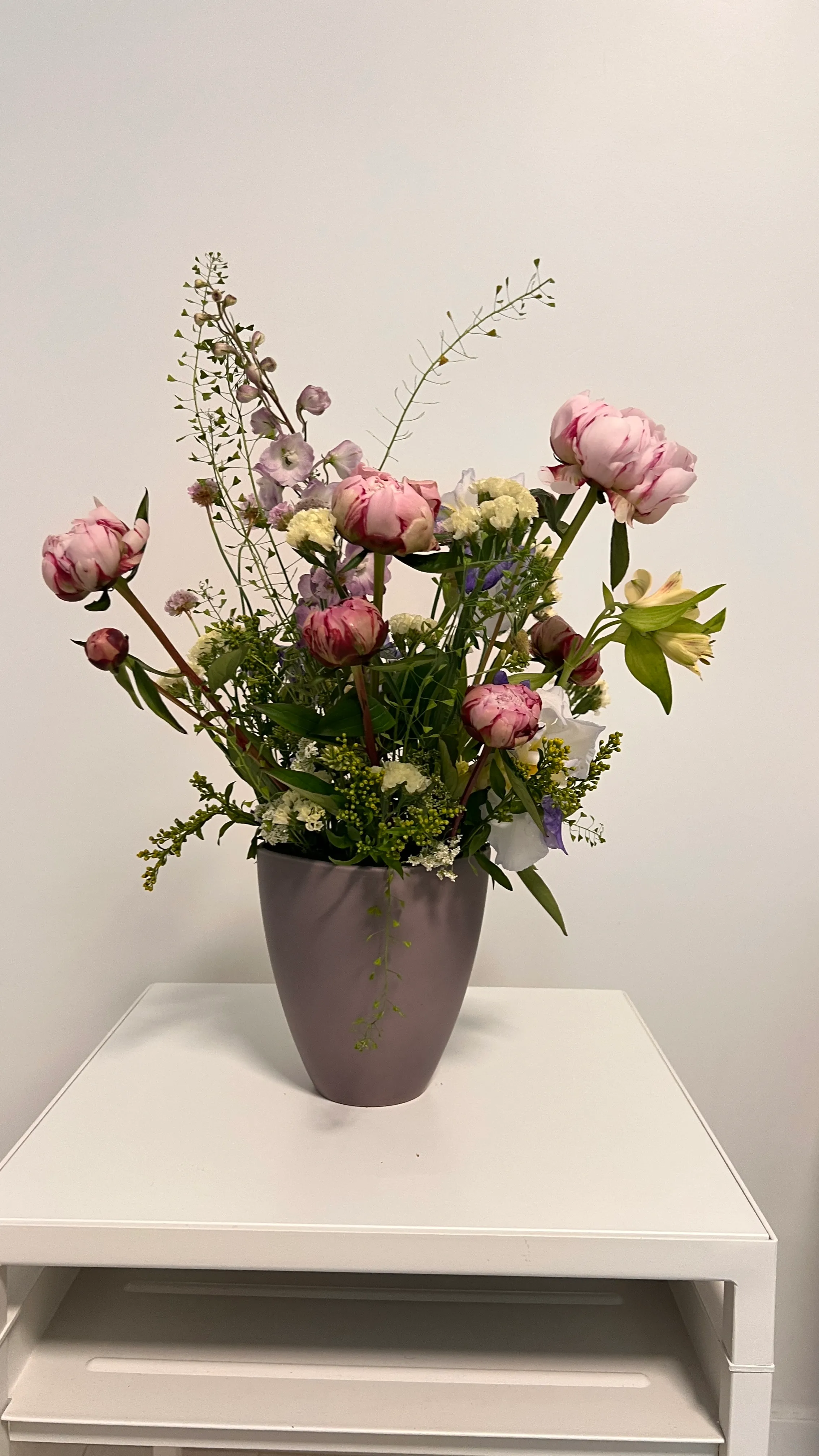 Blumenstrauß in lila Vase, weißer Hintergrund.