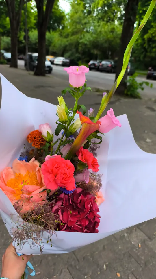 Blumenstrauß wird draußen auf dem Gehweg gehalten.