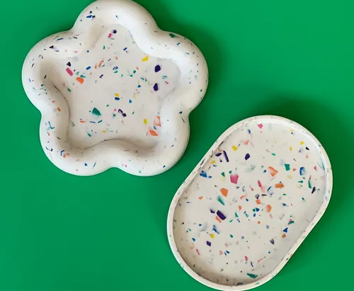 Zwei Terrazzo-Tabletts auf grünem Hintergrund.