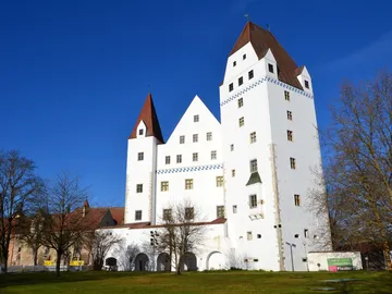 White castle stands under blue skies with trees.