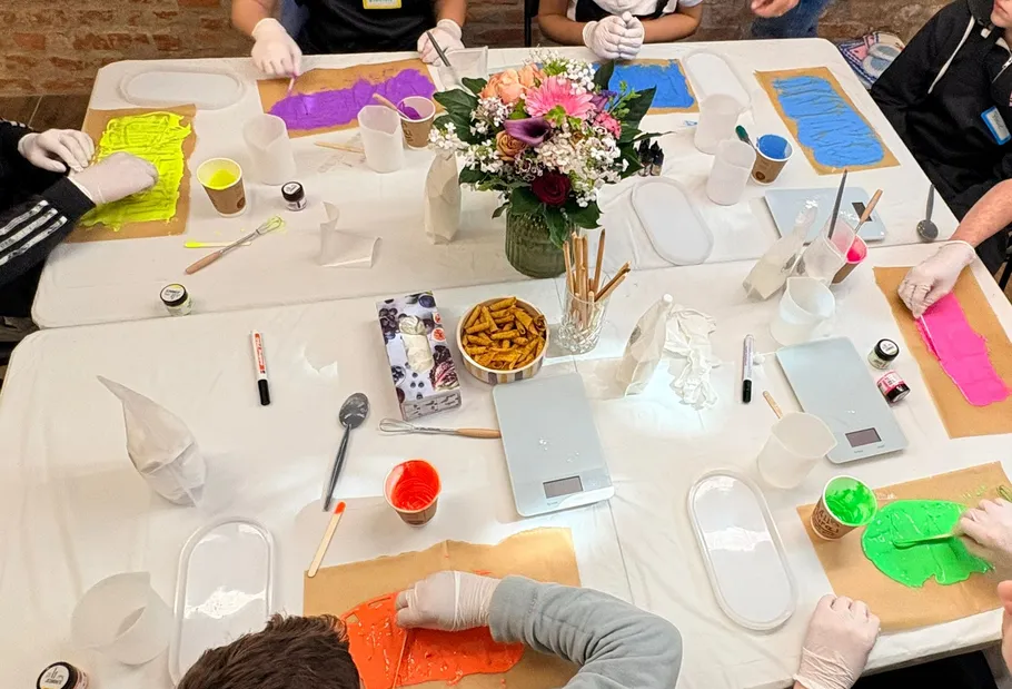 People making colored chocolate on table.