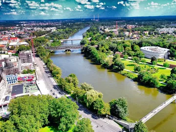 The river flows calmly between green banks and the urban landscape.