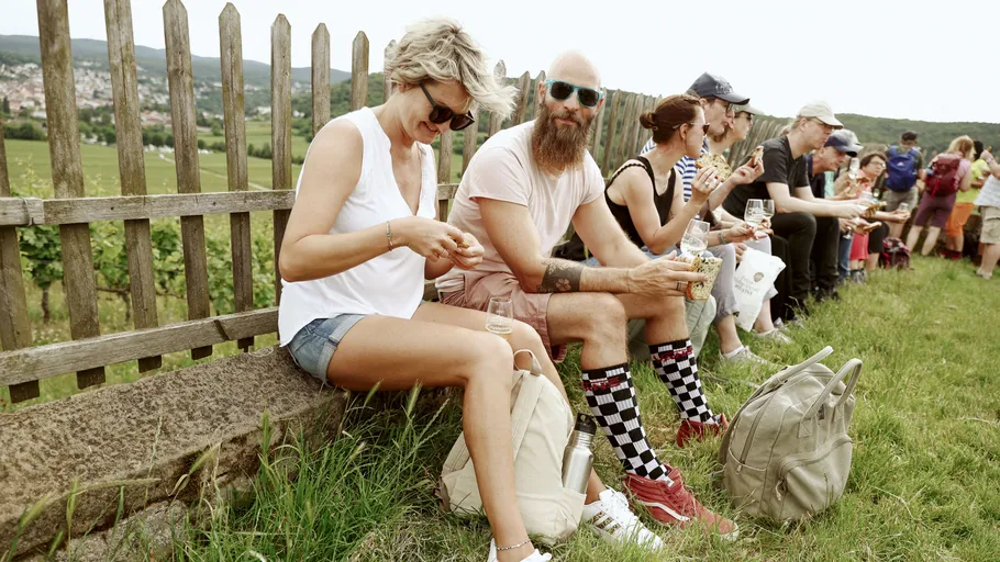 Menschen sitzen auf Gras und essen im Freien.