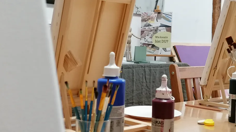Kunststudio mit Staffeleien, Farben und Pinseln.
