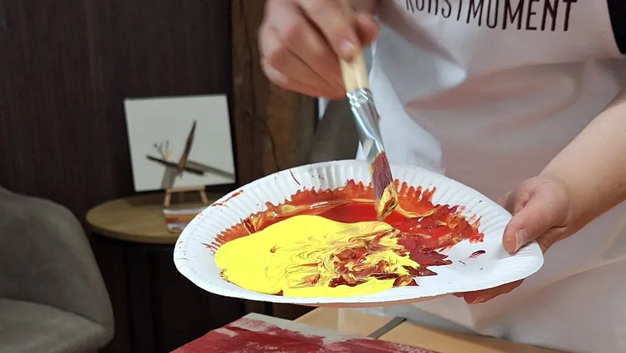 Person mixing paint on a paper plate.