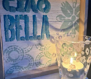 Candle beside Ciao Bella wooden sign.