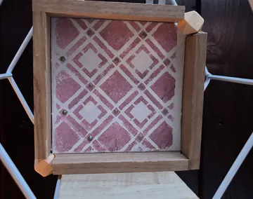 Holzgerahmte rosa gemusterte Fliese ausgestellt.