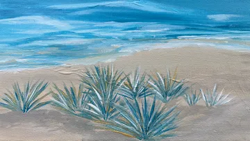 Plants on sandy beach, ocean in background.