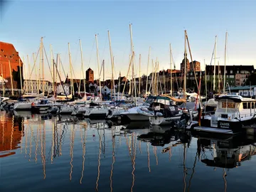 Boats are reflected in calm water, surrounded by docks.