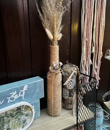Dekorative Vase mit Trockenblumen auf Regal.
