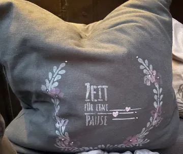 Decorative pillow with floral design and text.
