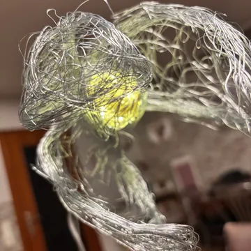 Drahtskulptur mit leuchtendem Licht im Innenraum.