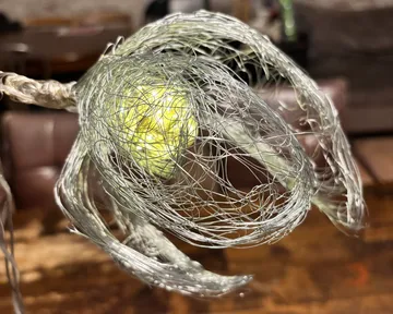 Drahtskulptur ähnelt einer leuchtenden Blume drinnen.