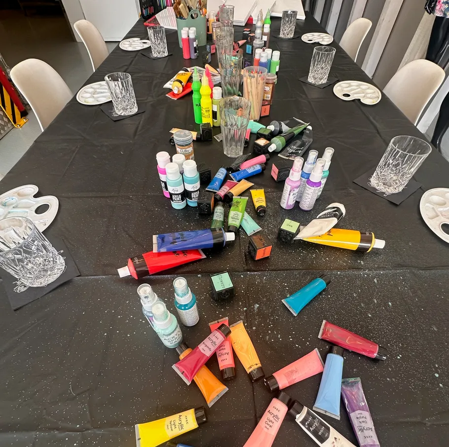 Art supplies scattered on black tablecloth.