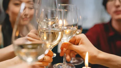 Gruppe stößt mit Weingläsern drinnen an.