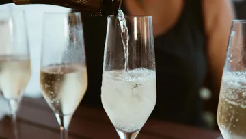 Champagner wird in Gläser auf Tisch gegossen.