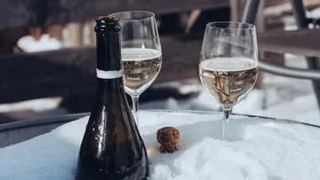 Champagnerflasche und zwei Gläser im Schnee.