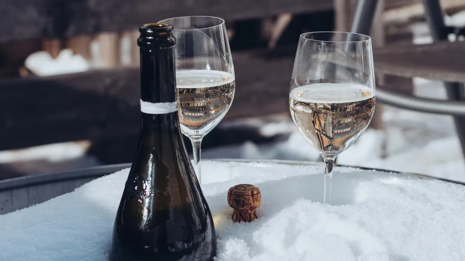 Champagne bottle and two glasses in snow.