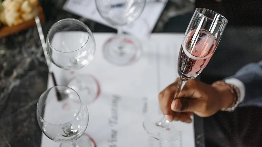 Person holding champagne flute beside empty glasses.