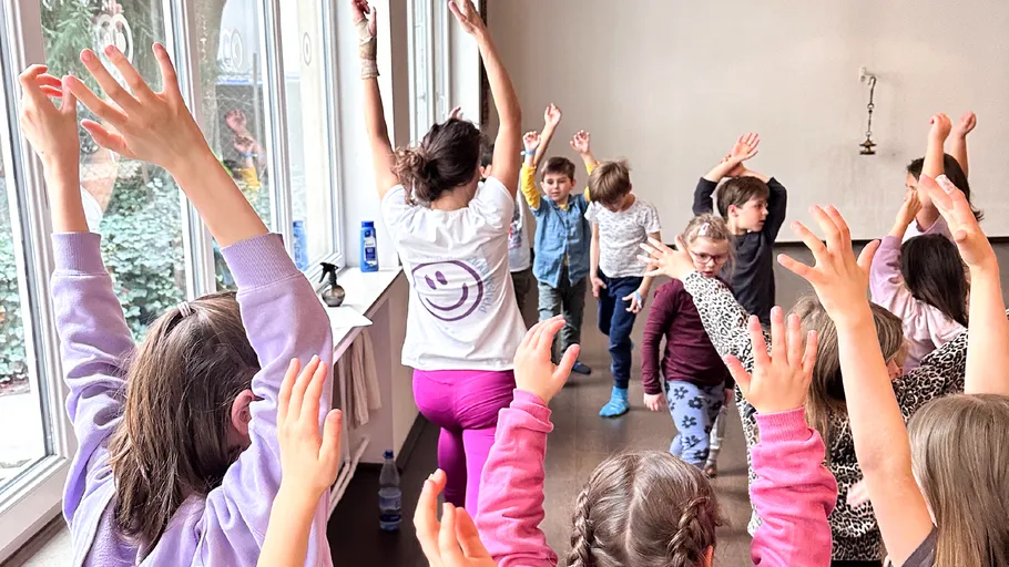 Children and teacher doing yoga in classroom.