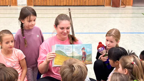Frau liest Kindern Bilderbuch vor.