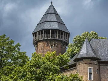 Tower surrounded by trees, under cloudy sky.