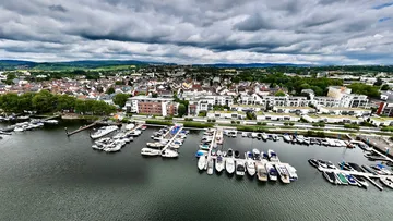 Boats docked in a marina cityscape cloudy sky.