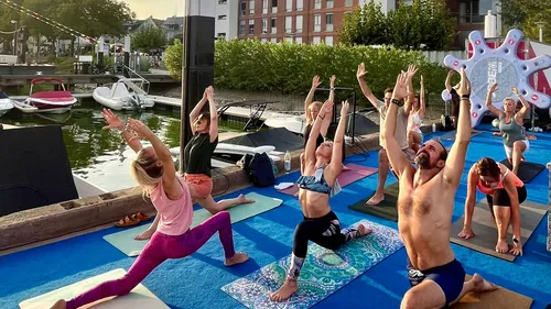 People practicing yoga on mats near a dock.