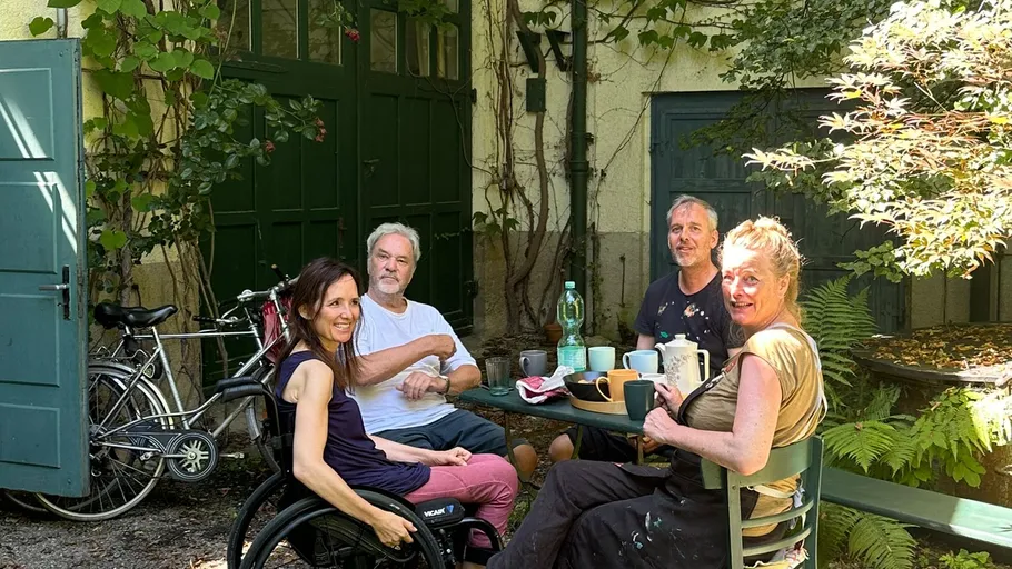 Four people sitting outdoors around table.