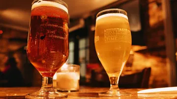 Two glasses of beer on wooden table.